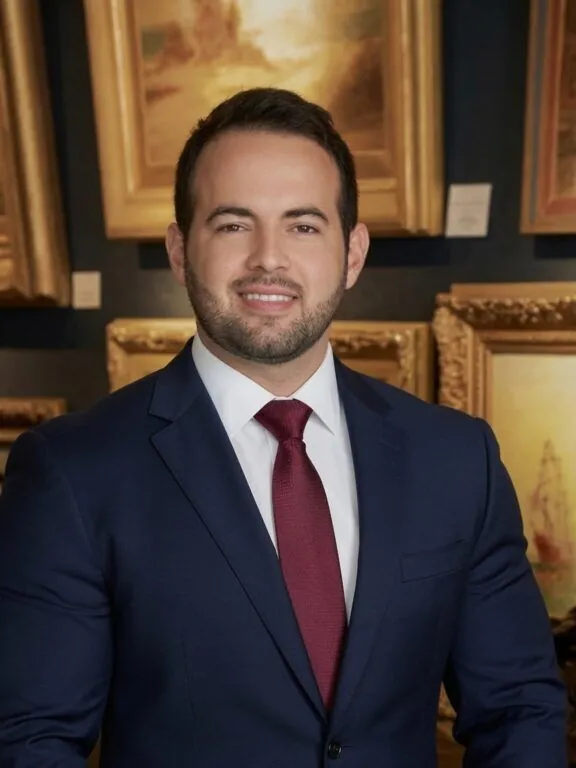 Austin Helmuth, Sarasota fine art appraiser, in front of framed paintings